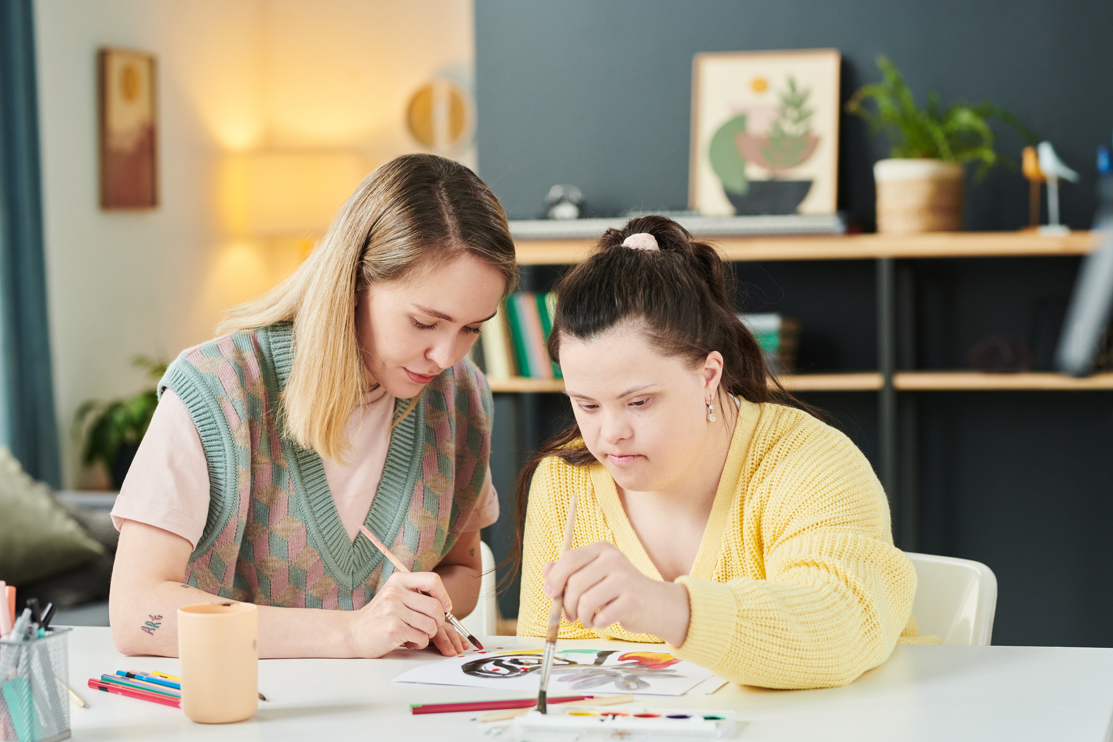 A support worker and an individual painting together